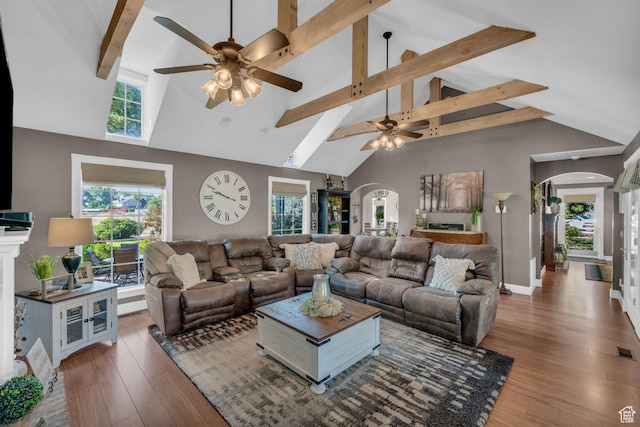 living room with arched walkways, dark wood-style flooring, and plenty of natural light