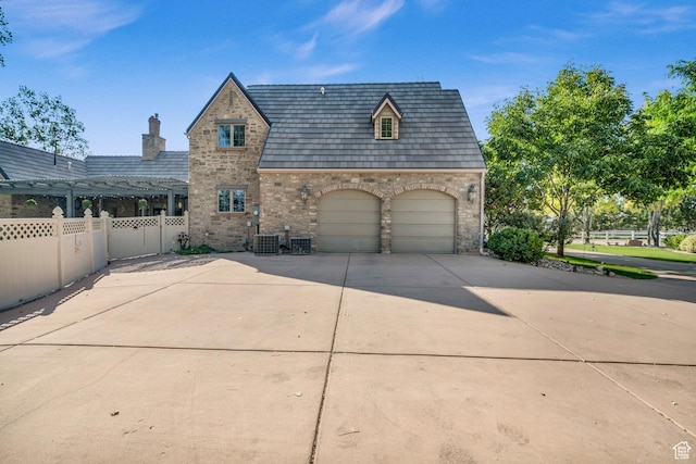 2218 W 2575 N, Cedar City, UT 84721 - view of front of home featuring a garage, concrete driveway, stone siding, fence, and central AC