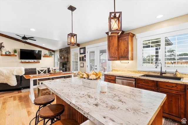 kitchen featuring a center island, lofted ceiling, a sink, open floor plan, and stainless steel dishwasher