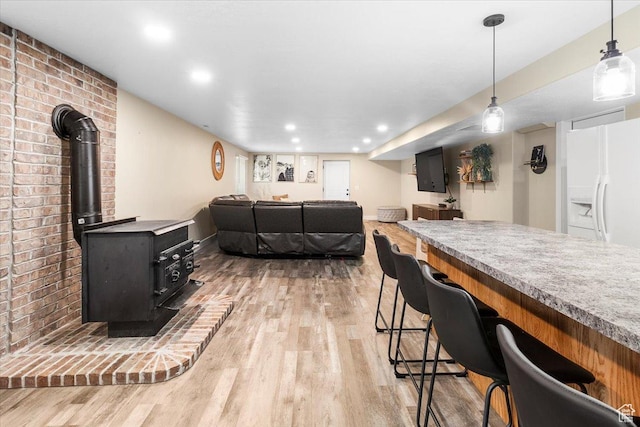 living area featuring light wood finished floors, a wood stove, and recessed lighting