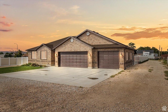 ranch-style house featuring brick siding, driveway, a garage, and fence