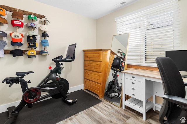 exercise area with baseboards, visible vents, and light wood finished floors