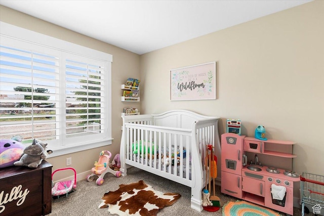 carpeted bedroom with a crib and baseboards