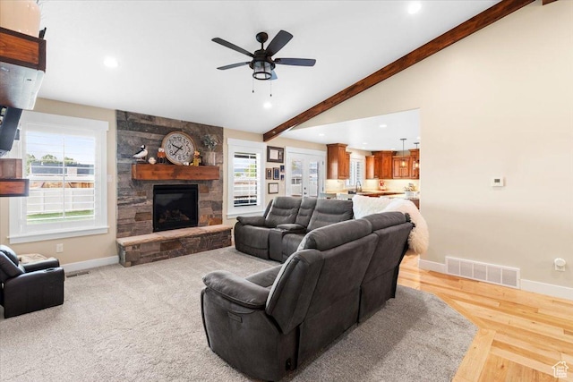 living area featuring a ceiling fan, vaulted ceiling with beams, a fireplace, baseboards, and visible vents