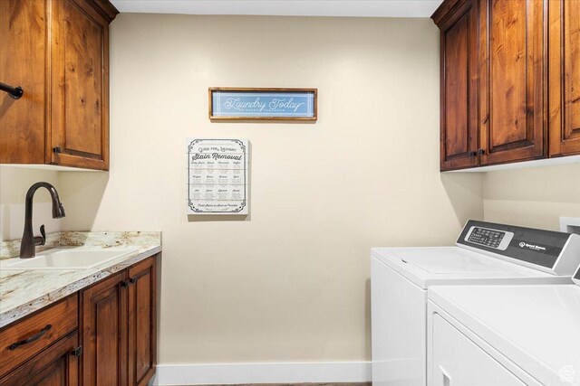 clothes washing area featuring a sink, cabinet space, and washer and dryer