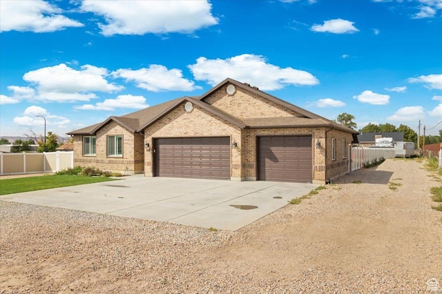 ranch-style house with brick siding, concrete driveway, fence, and an attached garage