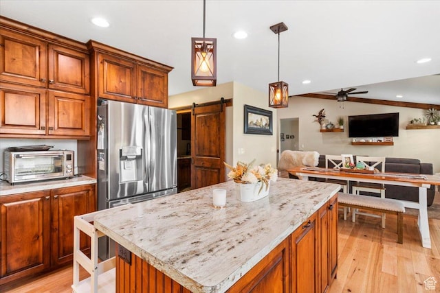 kitchen with open floor plan, light wood-style flooring, stainless steel fridge, and a toaster
