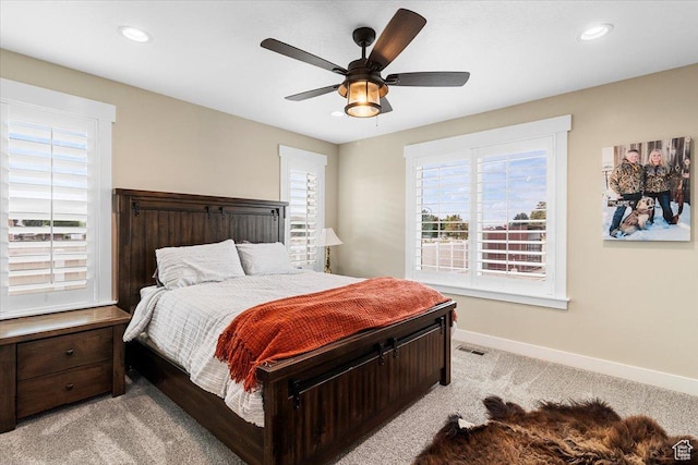 bedroom featuring light carpet, multiple windows, visible vents, and baseboards