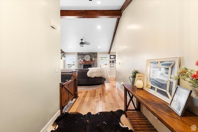 corridor featuring baseboards, vaulted ceiling with beams, and light wood-style flooring