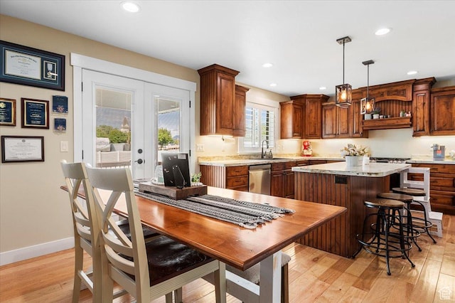 kitchen with light countertops, light wood finished floors, a center island, a sink, and stainless steel dishwasher