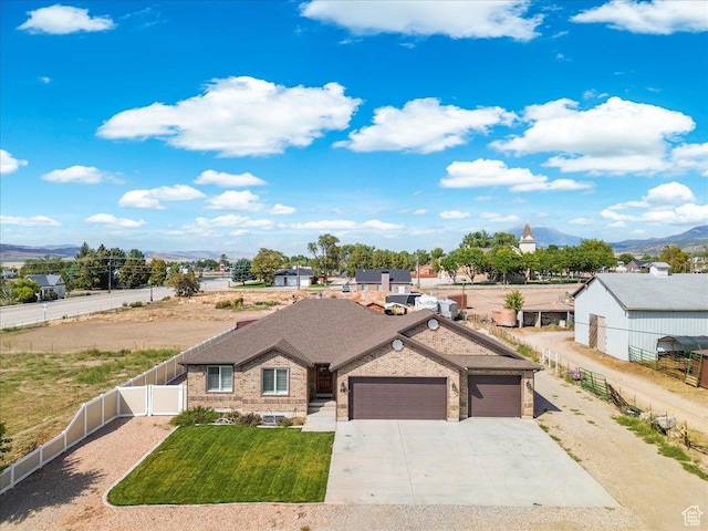 ranch-style home with an attached garage, a front yard, brick siding, driveway, and fence private yard