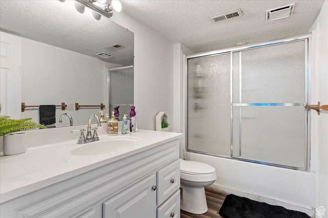 bathroom with visible vents, bath / shower combo with glass door, wood finished floors, and vanity