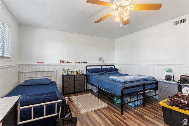 bedroom with visible vents, ornamental molding, wood finished floors, and a wainscoted wall