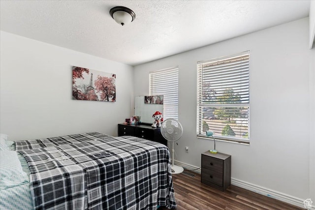bedroom featuring baseboards, dark wood-type flooring, and a textured ceiling