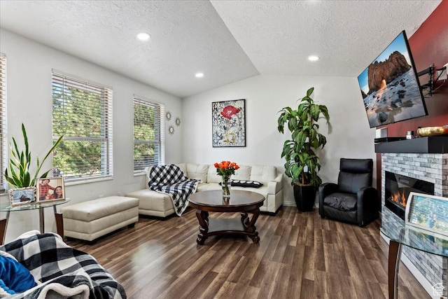 living area featuring a glass covered fireplace, lofted ceiling, a textured ceiling, and wood finished floors