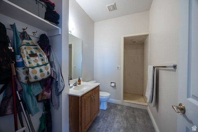 bathroom with walk in shower, toilet, hardwood / wood-style flooring, and vanity