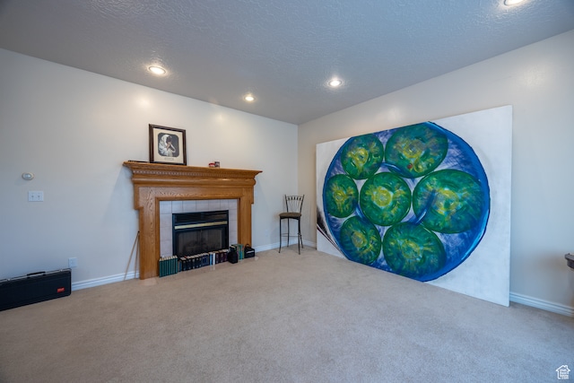 carpeted living room featuring a tile fireplace and a textured ceiling