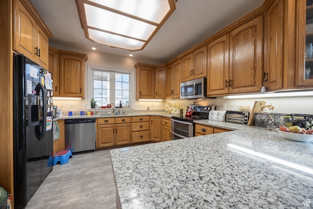kitchen with light stone countertops, stainless steel appliances, and sink