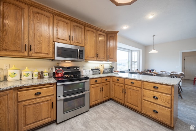 kitchen featuring appliances with stainless steel finishes, kitchen peninsula, decorative light fixtures, and light stone countertops