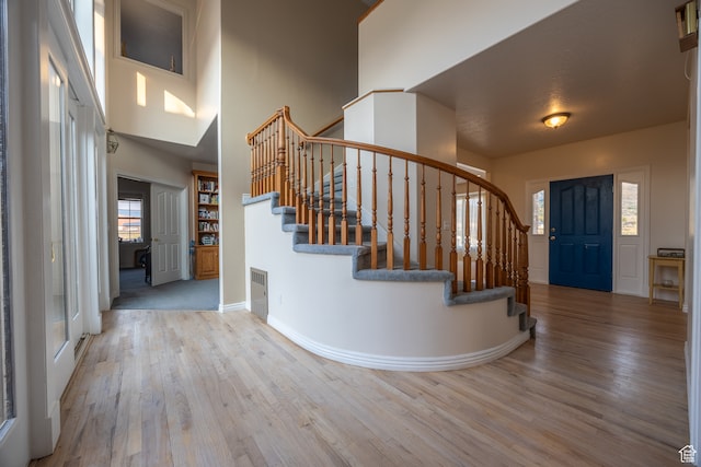 foyer entrance with a towering ceiling, a wealth of natural light, and light hardwood / wood-style floors