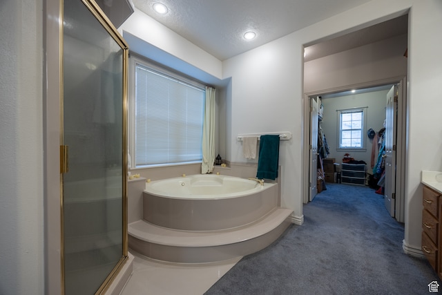 bathroom with vanity, a textured ceiling, and plus walk in shower