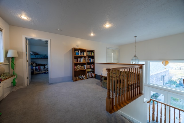 corridor featuring a textured ceiling, a chandelier, and carpet floors