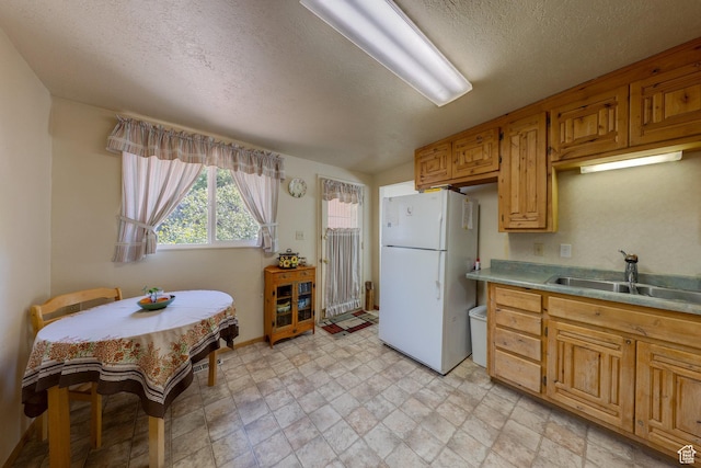 343 S Tusher St, Moab, UT 84532 - kitchen featuring freestanding refrigerator, a textured ceiling, light countertops, a sink, and baseboards