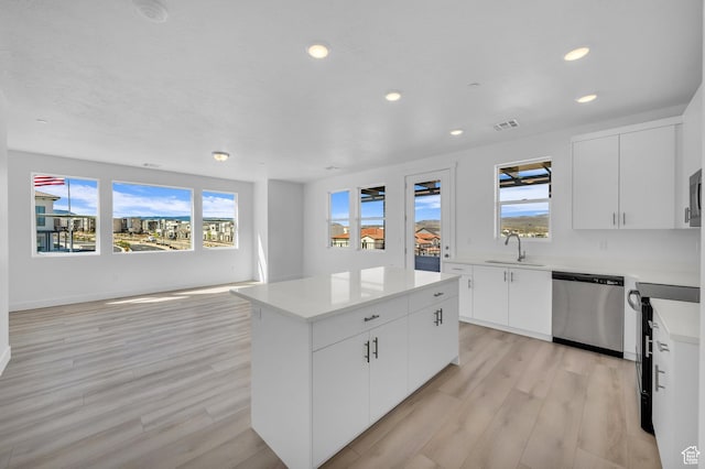 kitchen with a center island, light countertops, light wood-style flooring, appliances with stainless steel finishes, and a sink