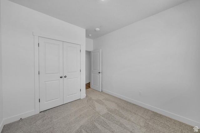 unfurnished bedroom featuring a closet, baseboards, and carpet