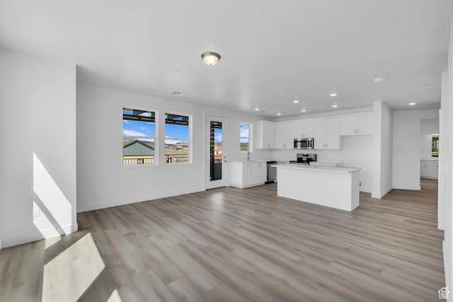kitchen featuring a center island, a healthy amount of sunlight, stainless steel appliances, and light wood-type flooring