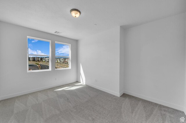 unfurnished room featuring visible vents, carpet, and baseboards