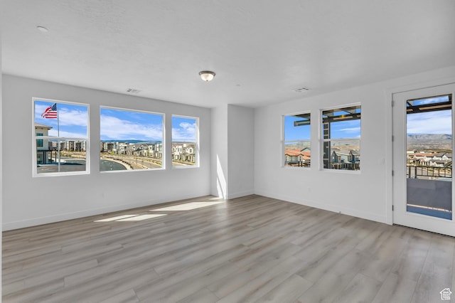 spare room with a wealth of natural light, visible vents, and light wood-style flooring