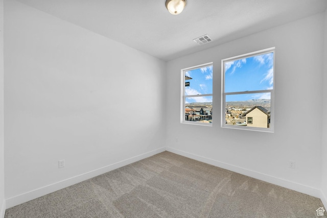 carpeted spare room with baseboards and visible vents