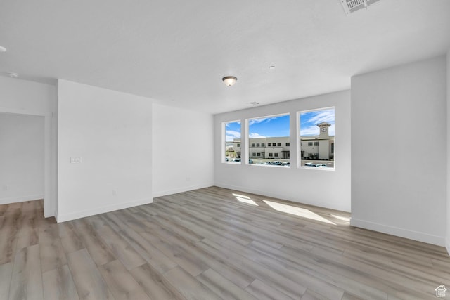 empty room featuring visible vents, baseboards, and wood finished floors