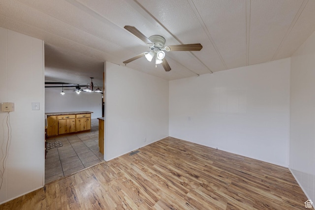spare room featuring light wood-type flooring, ceiling fan, and a textured ceiling