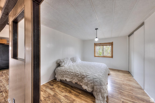 bedroom with a closet, light wood-type flooring, and a textured ceiling