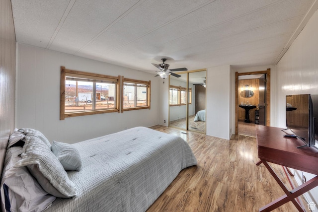 bedroom with a textured ceiling, wood finished floors, ceiling fan, and a closet
