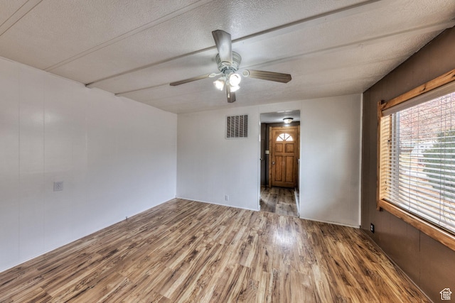 spare room featuring visible vents, ceiling fan, wood finished floors, and a textured ceiling