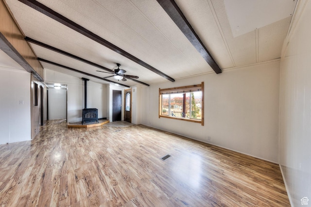 unfurnished living room featuring a wood stove, visible vents, a textured ceiling, and wood finished floors