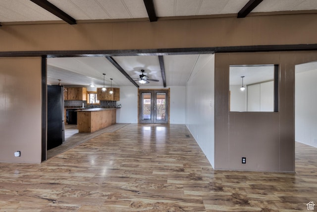 kitchen with open floor plan, brown cabinetry, light wood finished floors, and beam ceiling