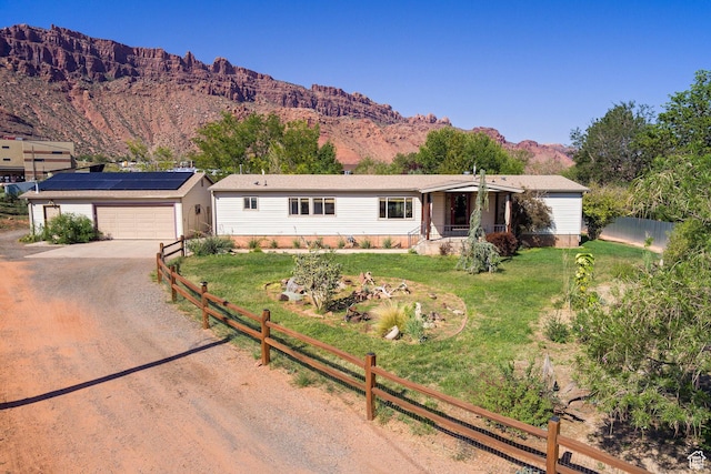 ranch-style home with an outbuilding, dirt driveway, a front yard, fence, and a mountain view