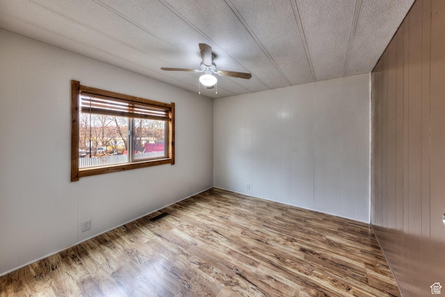 unfurnished room featuring a textured ceiling, wood finished floors, and ceiling fan