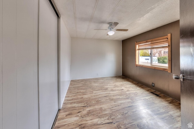 unfurnished room featuring a textured ceiling, light wood finished floors, ceiling fan, and visible vents