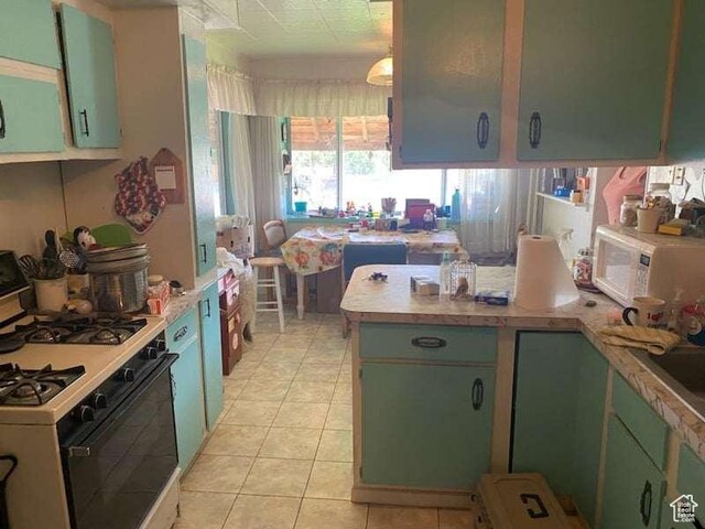 215 W 200 S, Duchesne, UT 84021 - kitchen with green cabinets, a peninsula, range with gas stovetop, and light countertops