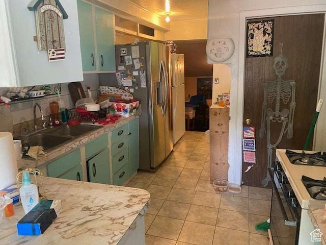 215 W 200 S, Duchesne, UT 84021 - kitchen with light countertops, light tile patterned flooring, white range with gas stovetop, green cabinetry, and a sink