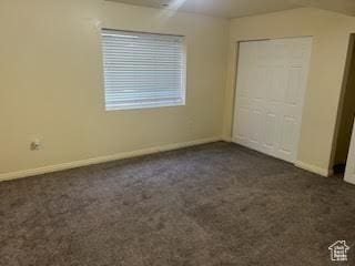 14112 S Senior Band Rd, Draper, UT 84020 - unfurnished bedroom featuring a closet, baseboards, dark carpet, and vaulted ceiling