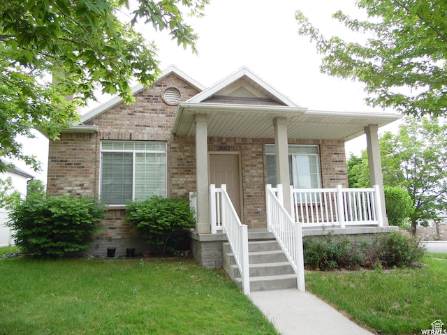 view of front of home featuring a front yard, covered porch, and brick siding