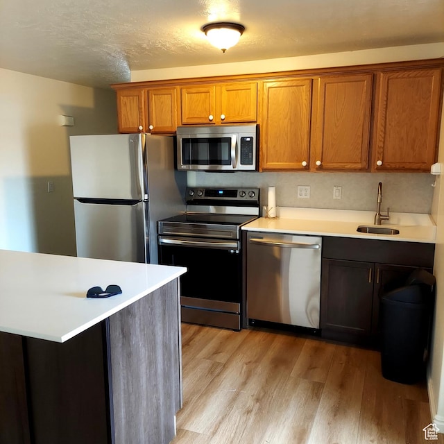 14112 S Senior Band Rd, Draper, UT 84020 - kitchen with light countertops, a sink, light wood finished floors, appliances with stainless steel finishes, and brown cabinetry