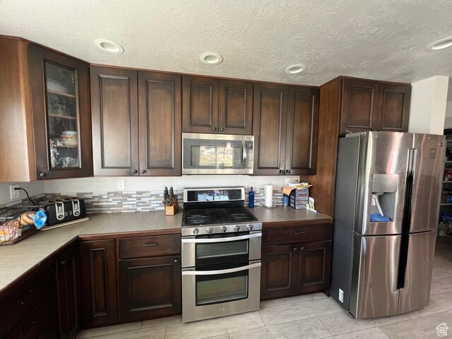 472 W 2300 S Unit 18, Richfield, UT 84701 - kitchen with light tile patterned floors, dark brown cabinets, stainless steel appliances, and glass insert cabinets