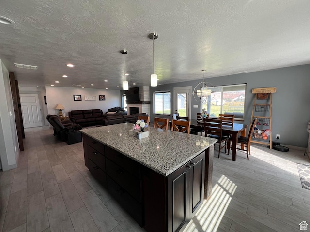 472 W 2300 S Unit 18, Richfield, UT 84701 - kitchen with visible vents, a kitchen island, wood tiled floor, a fireplace, and a textured ceiling